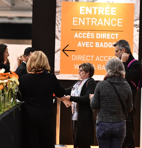 Hôtesse qui distribue des documents à l'entrée du salon