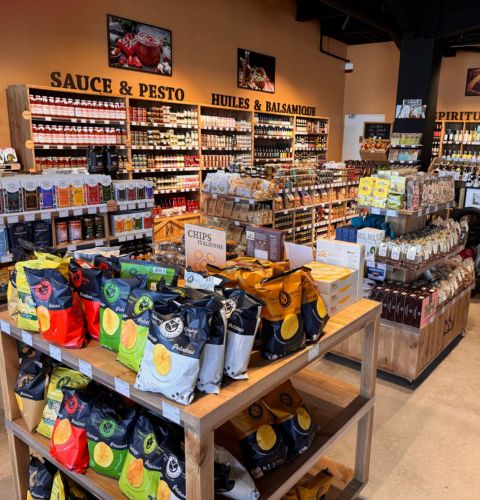 Warm interior of Bottega Bastiano store, shelves filled with sauces, pesto, and Italian products.