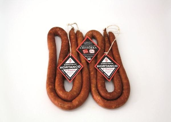 Two artisanal chistorras tied with red and black labels.