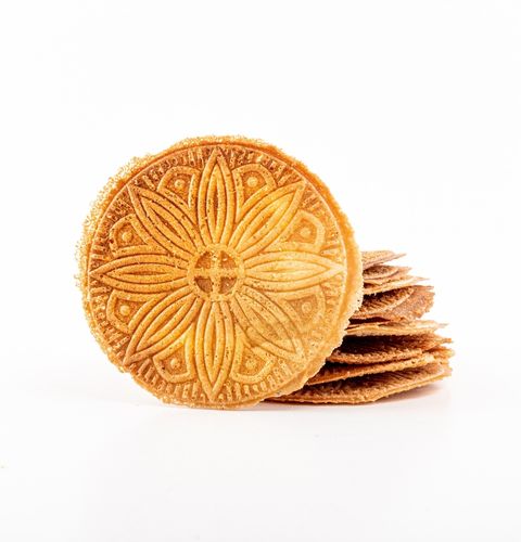 Biscuit rond doré aux motifs floraux, posé devant une pile de biscuits fins sur fond blanc.