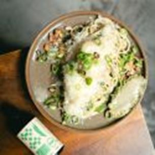 Assiette de risotto crémeux garni de fromage râpé, herbes fraîches et champignons sur table en bois.