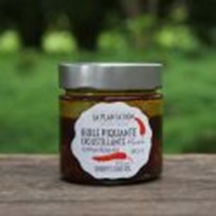 Jar of blood grapefruit jelly displayed outdoors with blurred green background.