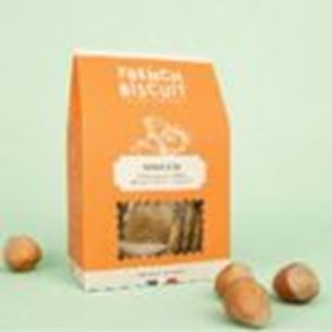 Boîte orange de biscuits salés posée sur fond beige avec noisettes autour du packaging.