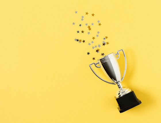 Silver trophy with star-shaped confetti on a bright minimalist yellow background.